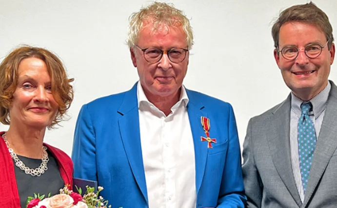 Bundesverdienstkreuz am Bande für Professor Dr. Boris Zernikow (Foto: Meike Haberstock) Prof. Dr. Boris Zernikow hat das Bundesverdienstkreuz am Bande verliehen bekommen, er steht zwischen seiner Ehefrau und dem Regierungspräsidenten der Bezirksregierung Münster, Andreas Bothe und lächelt in die Kamera.