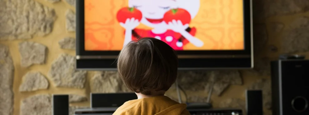 Ein Kind steht vor einem Fernseher.