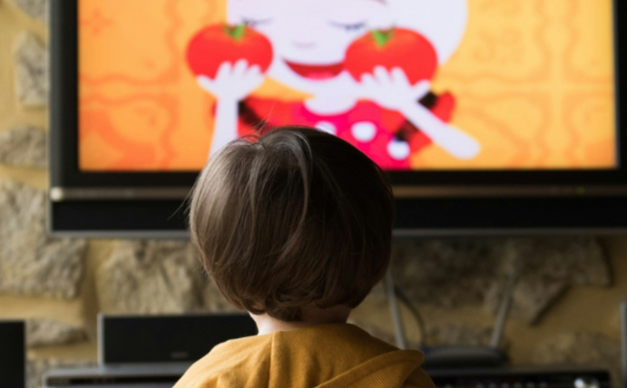 A child stands in front of a television.