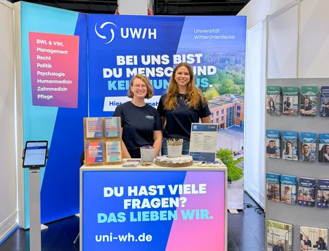 Zwei Personen am Messestand der Universität Witten/Herdecke
