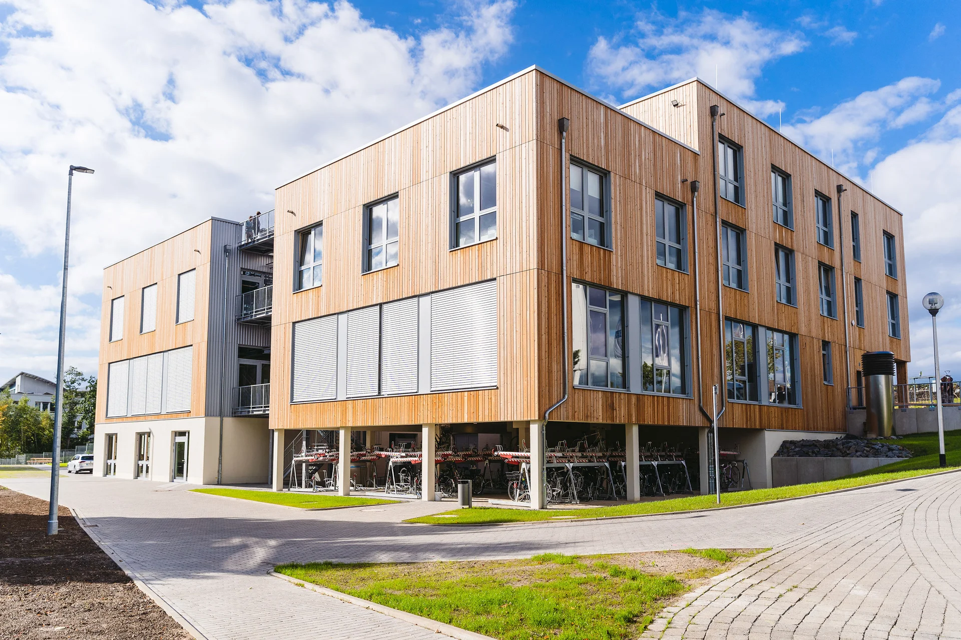 The new UW/H building is an eco-friendly timber structure that meets high sustainability standards. (Photo: UW/H | Johannes Buldmann) Rear view of the new UW/H building. The photograph offers a glimpse of the covered cycle car park and shows the eco-friendly timber façade.