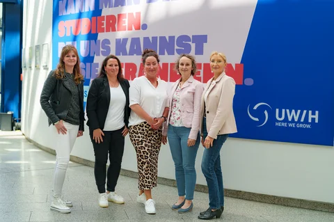 Gruppenfoto mit fünf Personen vor einem UW/H-Banner