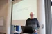Prof. Dr. Carsten Rensinghoff gibt Einblick in das Thema „Menschen mit Behinderung in der ärztlichen Sprechstunde“ (Foto: UW/H | Kristina Eichhorn) Ein Mann steht an einem Rednerpult mit Notebook. Hinter ihm wird eine Präsentation an die Wand projiziert.