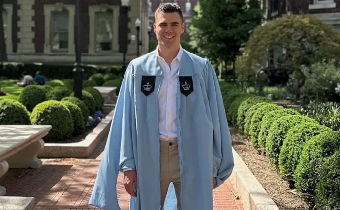 Ein Student steht auf einem Unicampus.