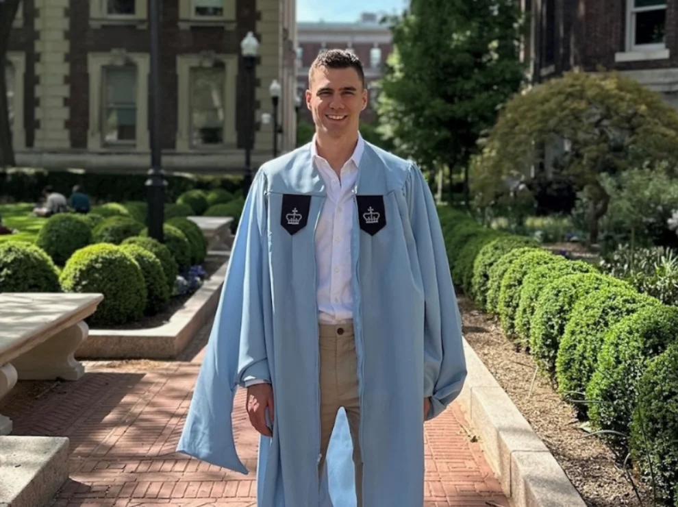 Ein Student steht auf einem Unicampus.