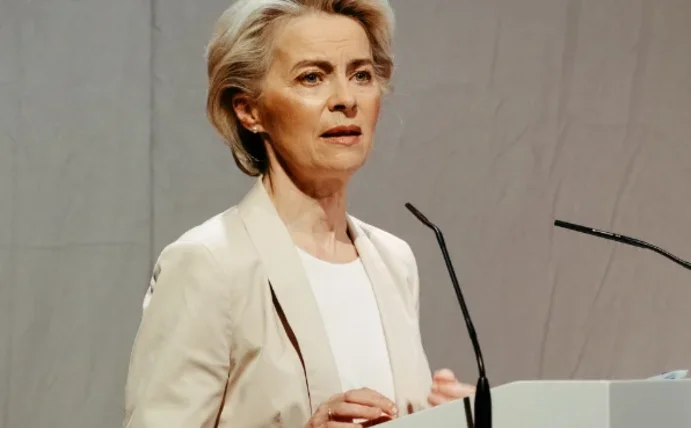 Eine Frau steht an einem Rednerpult und spricht in ein Mikrofon.