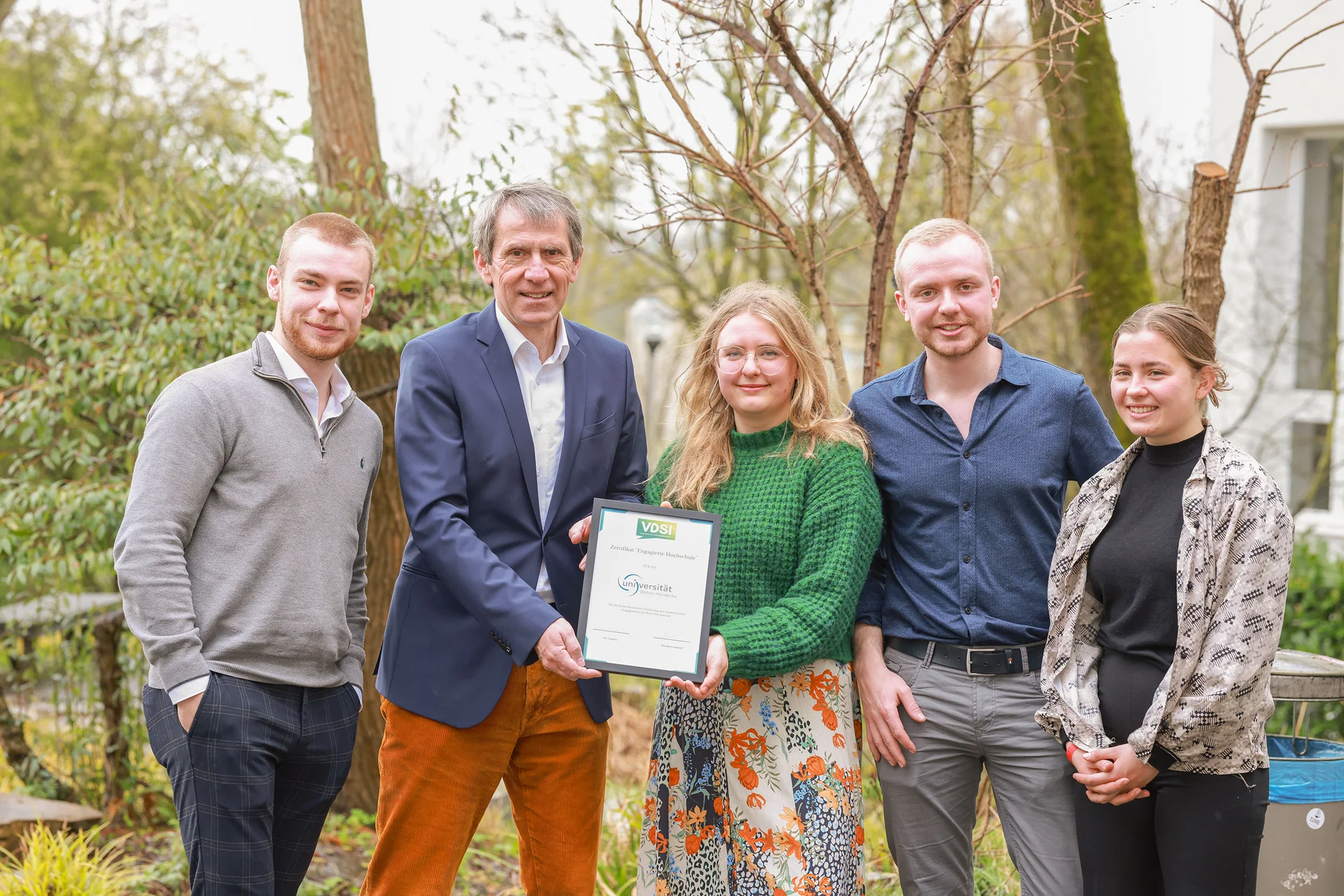 The UW/H has been awarded the ‘Committed University’ certificate in recognition of its community engagement work. (Photo: Tall Trees Media | Felina Gust) Group photo in the university gardens. The group is holding the ‘Committed University’ certificate.