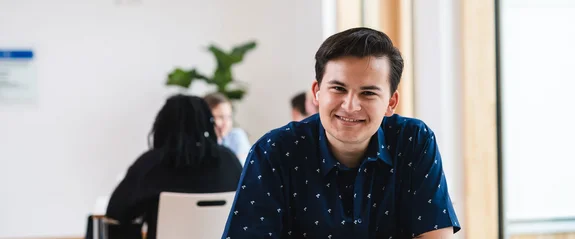 Management & Psychologie (B. Sc.) studieren an der UW/H (Foto: UW/H | Johannes Buldmann) Ein Management & Psychologie (B. Sc.) Student sitzt im Lernflur und schaut direkt in die Kamera.