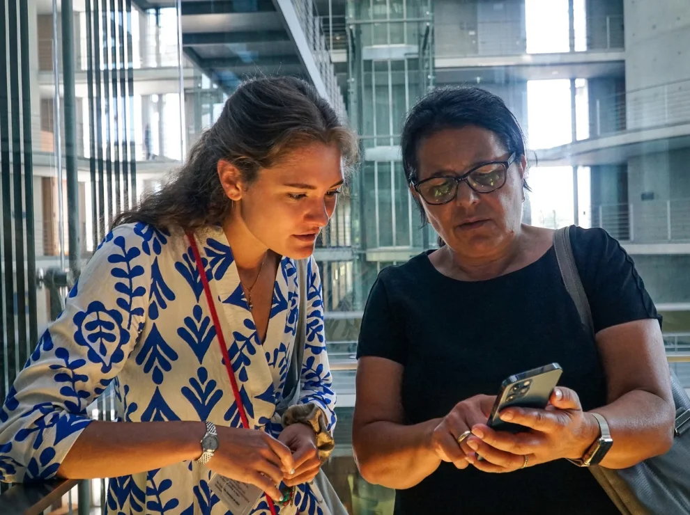 Frederike Westphalen und Gülistan Yüksel schauen zusammen auf ein Smartphone.