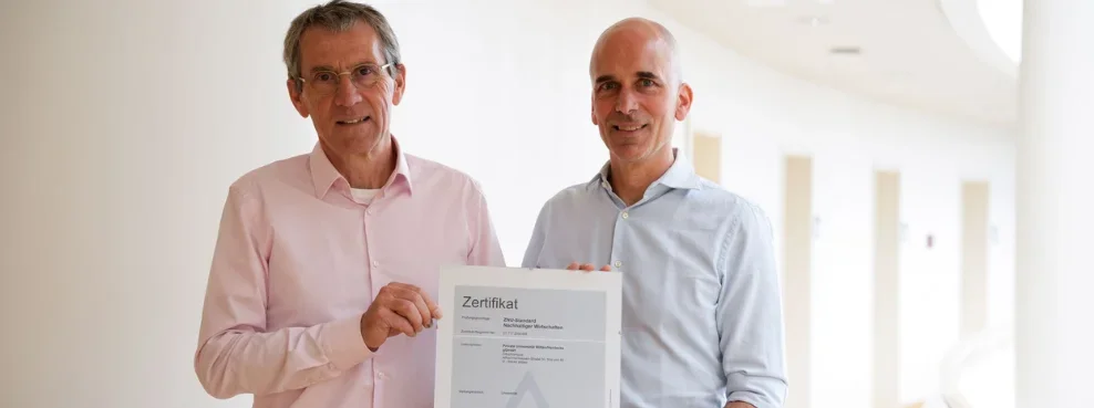 Zwei Personen halten ein Zertifikat in die Kamera.