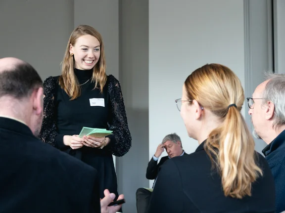 Nicole Steller steht lächelnd vor einem Publikum und hält einen Vortrag. In den Händen hält sie Moderationskarten.