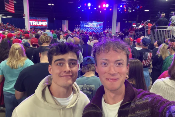 Zwei Personen machen Selfie vor einem gefüllten Saal.