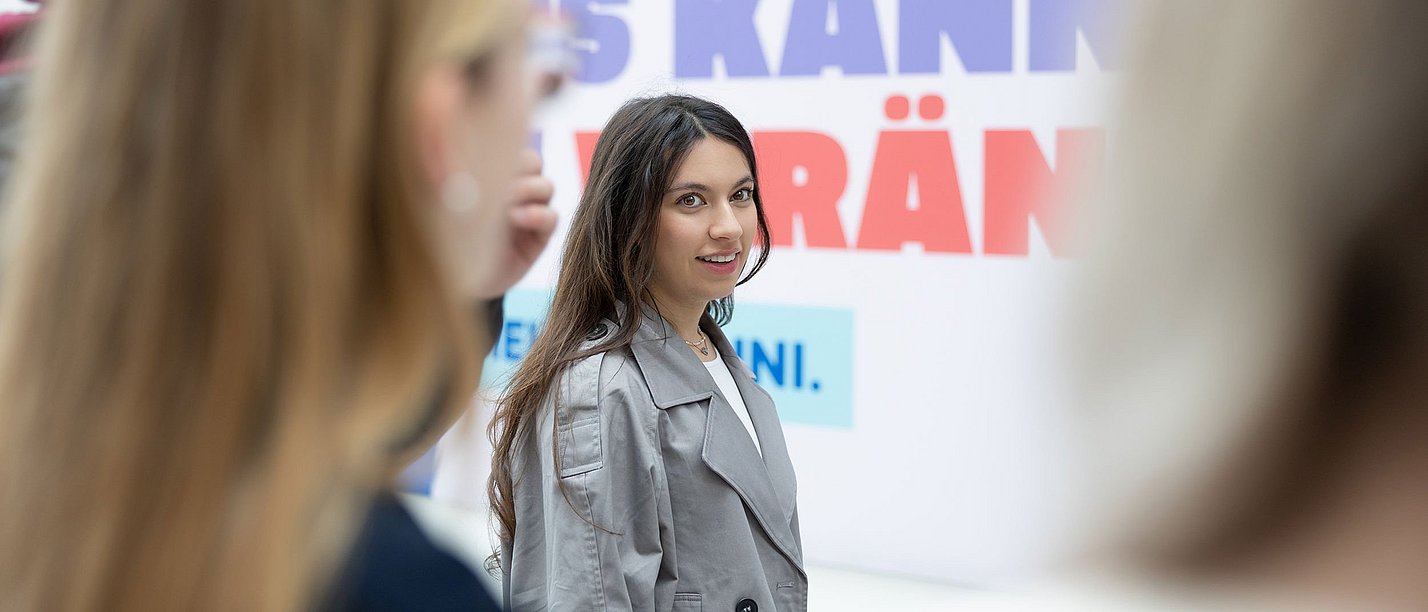 Finde Ideen für deinen beruflichen Werdegang in unserem Orientierungsworkshop. (Foto: UW/H | Michael Schwettmann) Eine Gruppe junger Frauen steht vor einem Plakat.