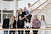 Gruppenfoto von neun Personen, die teils in einer Reihe, teils auf einer Treppe im Hintergrund stehen.