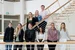 Gruppenfoto von neun Personen, die teils in einer Reihe, teils auf einer Treppe im Hintergrund stehen.