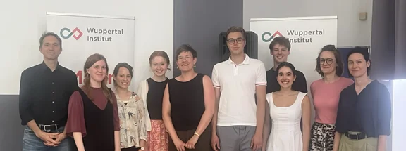 Auf dem Bild ist eine Gruppe von Menschen vor dem Banner des Wuppertal Instituts zu sehen 