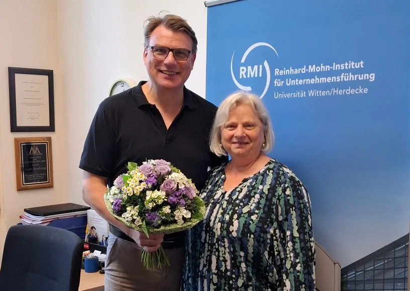 Die Geschäftsführerin der WIGE-Fakultät gratuliert Guido Möllering mit einem Blumenstrauß