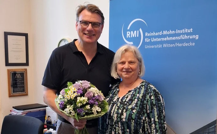 Professor Guido Möllering leitet seit 10 Jahren das Reinhard-Mohn-Institut als Direktor Die Geschäftsführerin der WIGE-Fakultät gratuliert Guido Möllering mit einem Blumenstrauß