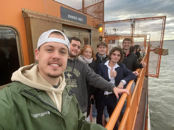 Studierende stehen an der Reling einer Fähre und lächeln in die Kamera.