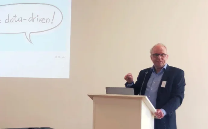 Ein Mann steht an einem Rednerpult und hält eine Präsentation.