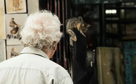 Symbolbild eines älteren Mannes vor einem Schaufenster mit Gemälden
