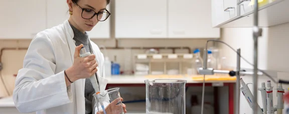 The UW/H offers a wide range of career opportunities in academia. (Photo: UW/H | Michael Schwettmann) A young woman is standing in a laboratory, carrying out experiments.