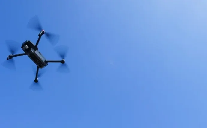 Man sieht eine Drohne am blauen Himmel.