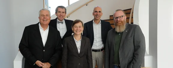 Five people standing next to each other on a landing