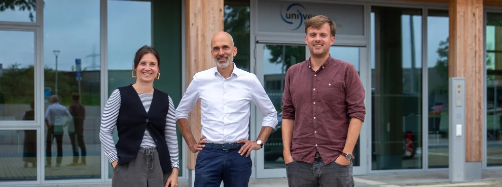 Drei Personen lächeln in die Kamera.