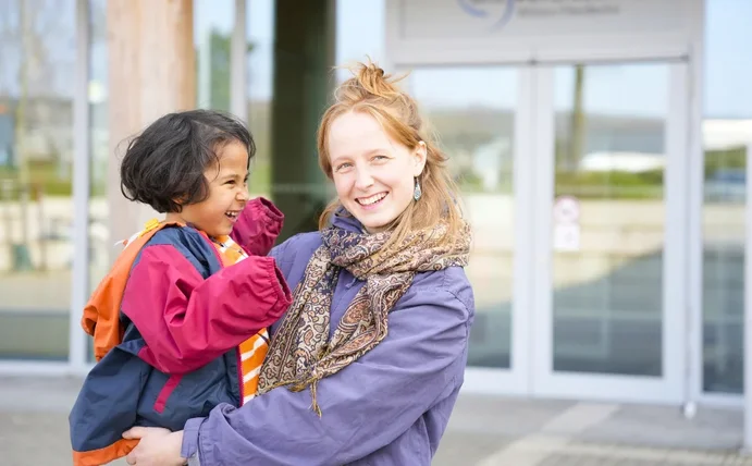 Elsa Heinsius mit Sohn Oskar vor dem Eingang des Holzgebäudes der Uni Witten/Herdecke.