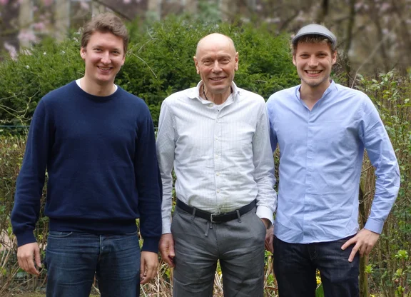 Foto von drei Männern, die nebeneinander stehen und in die Kamera lächeln.