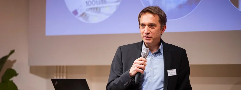 Referent am Mikro vor einer Beamer-Präsentation