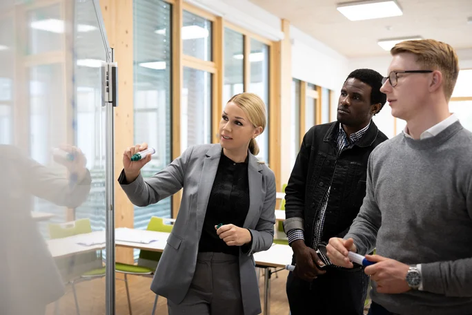 Seminar im Studiengang Management & Psychologie (B. Sc.) an der UW/H (Foto: UW/H | Michael Schwettmann) Eine Professorin erläutert zwei Studenten des Fachs Management & Psychologie (B. Sc.) ein Thema am Whiteboard.