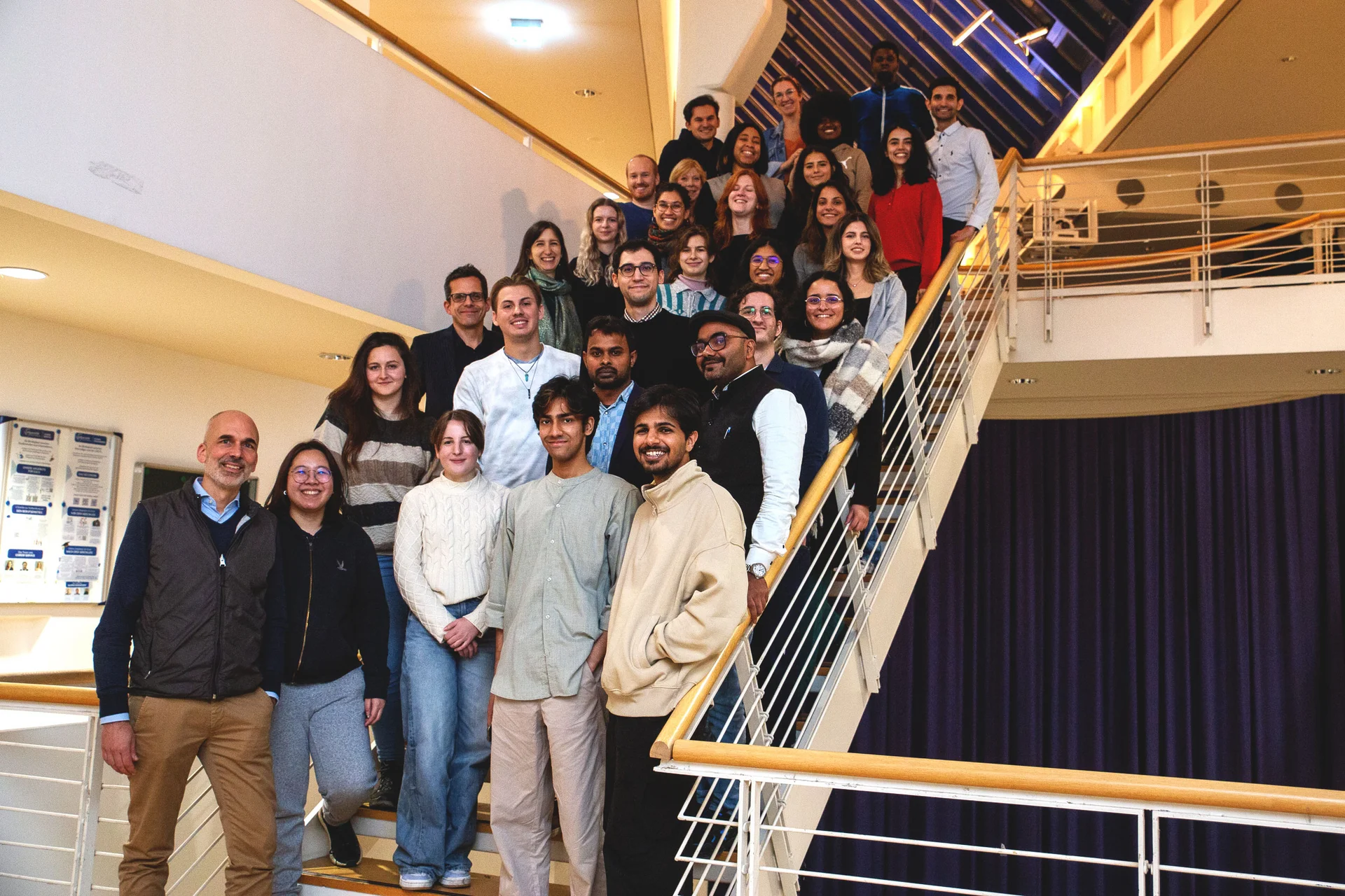 Die UW/H heißt ihre internationalen Studierenden willkommen. (Foto: UW/H) Eine Gruppe internationaler Studierenden posiert hintereinander aufgereiht auf einer Treppe für das Foto.