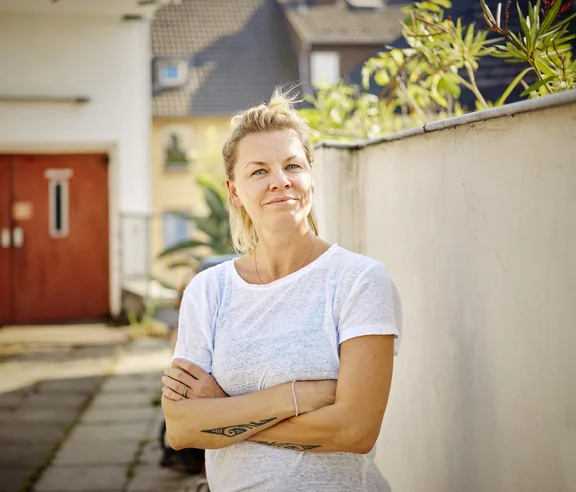 Portrait einer Frau vor einer Hauseinfahrt.