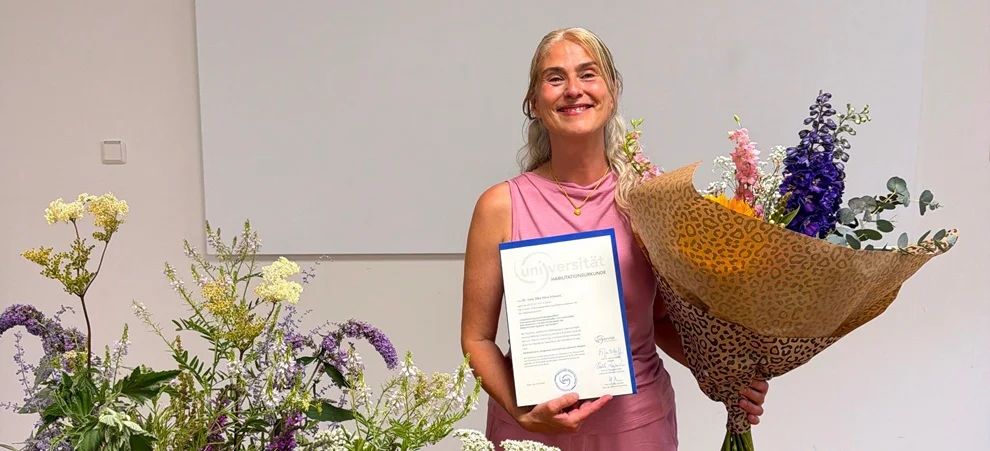 PD Dr. med. Silke Schwarz mit ihrer Urkunde und einem Blumenstrauß in der Hand auf der Bühne