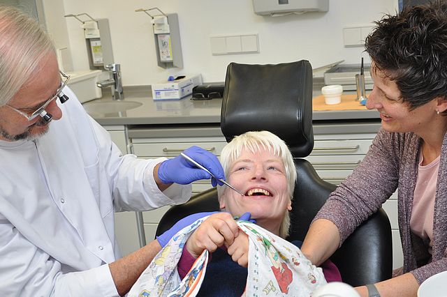 Eine Patientin wird im Beisein ihrer Betreuungsperson von einem Zahnarzt untersucht.