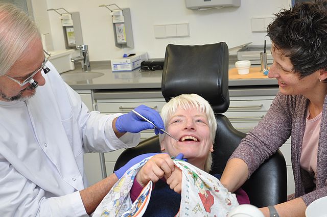Eine Patientin wird im Beisein ihrer Betreuungsperson von einem Zahnarzt untersucht.