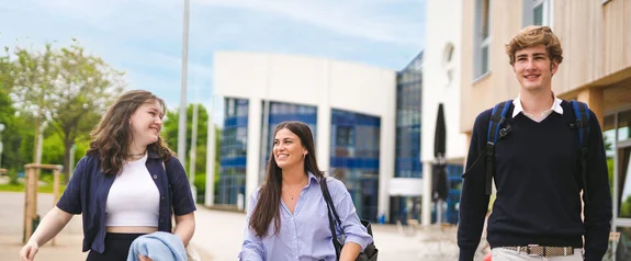 Three people in front of the university building