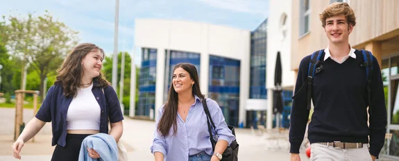 Three people in front of the university building