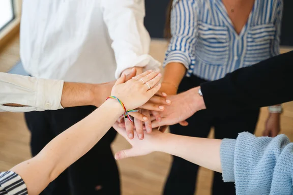 The UW/H’s support services are on hand to help with any enquiries. (Photo: UW/H | Johannes Buldmann) Several people stand in a circle and place their hands on top of one another.