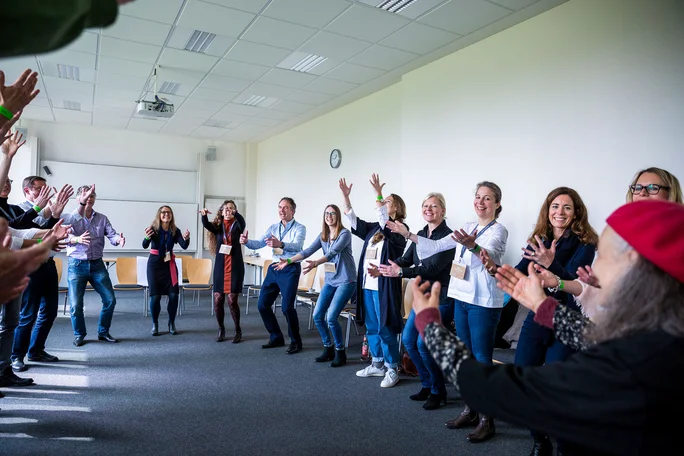 A big reunion at the alumni gathering (Photo: UW/H | Michael Schwettmann) A group of people are standing in a circle and raising their hands to do the La Ola.