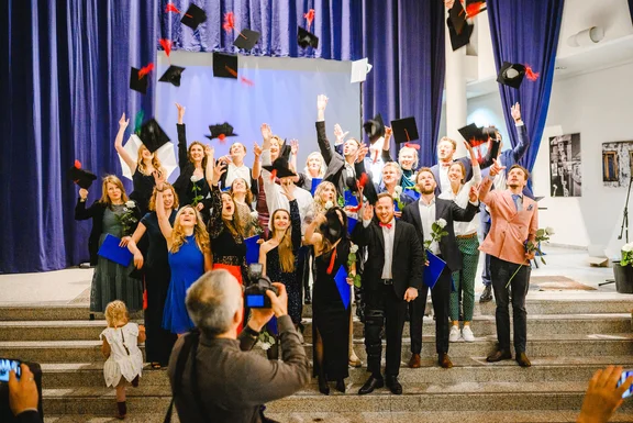 Foto von einer Absolvierendenfeier. Die Studierenden werfen ihre Absolvierendenkappen in die Luft.