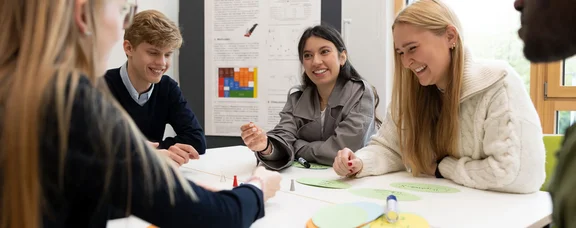 Eine Gruppe junger Menschen sitzt an einem Tisch und arbeitet zusammen.