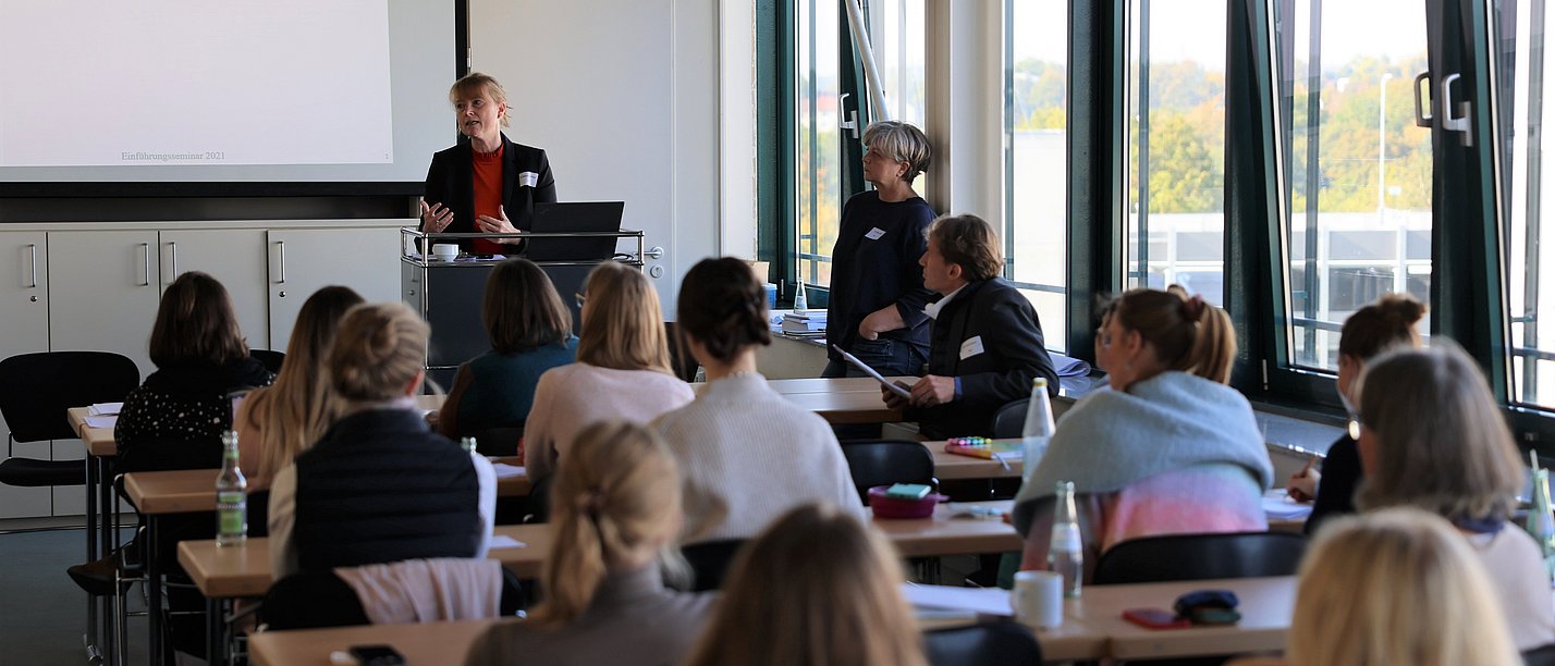 IGIM Einführungsseminar an der UW/H (Foto: David Roeder) Promovierende sitzen in einem Seminarraum und hören der Dozentin zu, die vorne steht.
