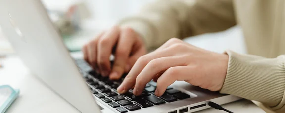 Nahaufnahme von Händen, die auf einem Laptop tippen.