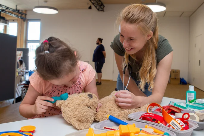 Eine Frau und ein Kind untersuchen einen Teddybären mit medizinischem Equipment