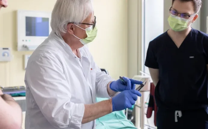 Lehrsituation in der Zahnmedizin. Ein Professor demonstriert den korrekten Umgang mit Instrumenten vor seinen Studierenden.