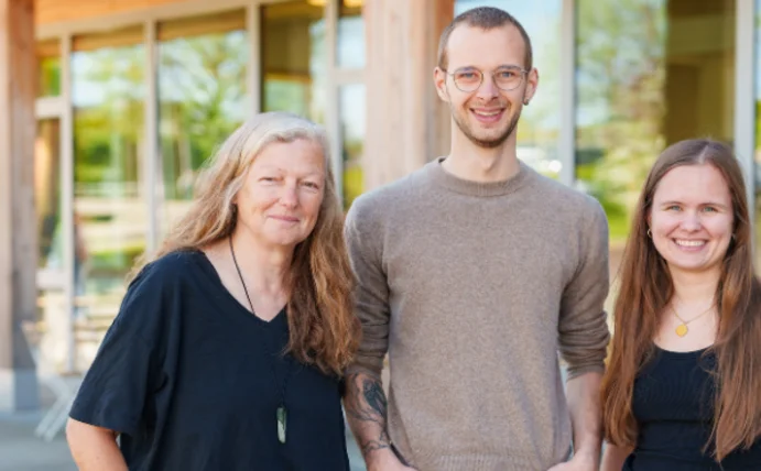 Projektteam ARAP (Foto: UW/H) Man sieht drei Menschen, die vor der Universität stehen und in die Kamera lächeln.