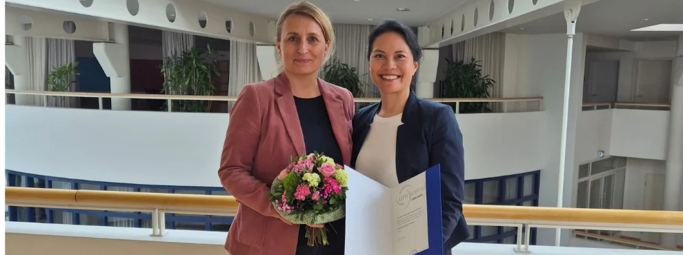 You see two women smiling warmly at the camera.